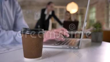 办公室里摆着一杯咖啡，商人正在用手提电脑<strong>打字</strong>，他的同事正在与科技建立<strong>联系</strong>
